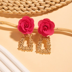 Détail de boucles d'oreilles rose en tissu vintage avec relief en métal doré sur bois