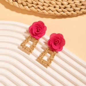 Gros plan de boucles d'oreilles rose avec cadres rectangulaires dorés sur un présentoir