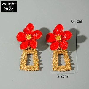 Détail de boucles d'oreilles rétro avec fleurs rouges et pendentifs en métal doré