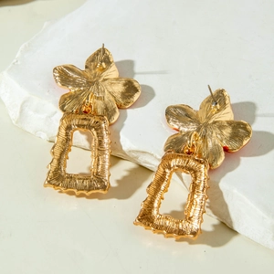 Détail des boucles d'oreilles fleur dorée avec texture en relief et pendentif rectangle