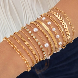 Détail d'un ensemble de bracelets à chaînes dorées multicouches avec perles et cœurs