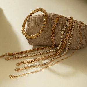 Détail d'un ensemble de 5 bracelets dorés avec strass présentés sur un support minéral