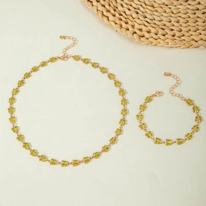 Detalle del conjunto de collar y pulsera de mariposa dorada con cristales verdes y broche