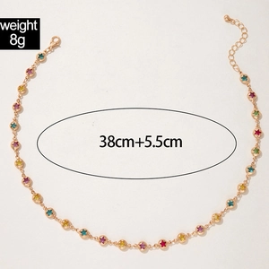 Detalle del collar dorado con estrellas de colores mostrando longitud 38cm más 5,5cm