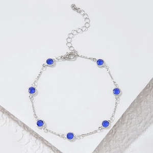 Detalle de pulsera de cadena plateada con siete cristales azules redondos y mosquetón
