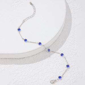Detalle de pulsera de cadena plateada con piedras azules, cierre de langosta y extensión