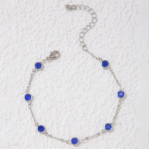 Detalle de collar de cadena plateada con pedrería azul redonda y cierre de langosta