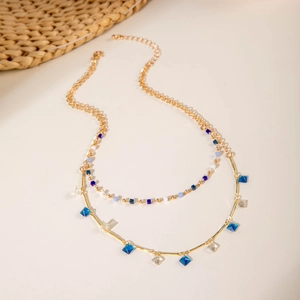 Detalle de un collar de dos capas chapado en oro con pequeños cristales azules