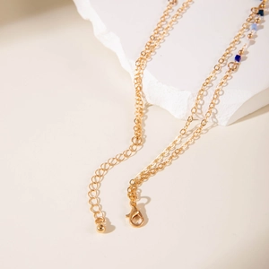 Detalle de un collar gargantilla dorado con cuentas cuadradas azules y cierre de langosta