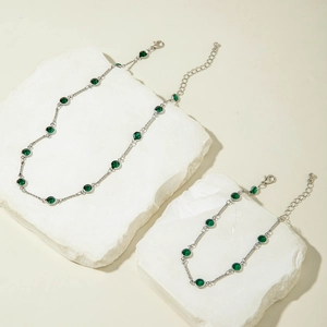 Detalle del conjunto de collar y pulsera plateado con cristales redondos en verde oscuro