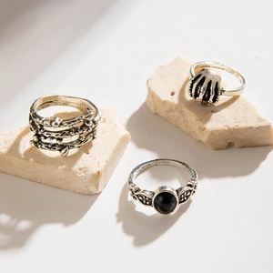 Close-up of vintage gothic rings set featuring skull hand and black gemstone on stone base