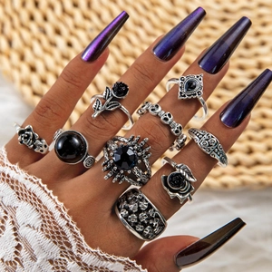 Close-up of vintage silver gothic ring set featuring skulls, black roses and dark gemstones
