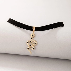 Detail van een fluwelen choker met gouden slangenhanger en zwarte strass-steentjes