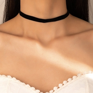 Close-up van een slanke zwarte fluwelen choker gedragen door een model in zonlicht