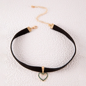 Detail van zwarte fluwelen choker met gouden hartvormige hanger en turquoise stenen