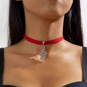 Close-up van een rode fluwelen choker met een gedetailleerde zilveren slangenhanger
