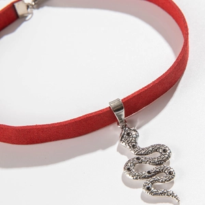 Detail van rode fluwelen choker met zilveren slangenarmband en zwarte steentjes