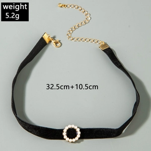 Detailweergave van zwarte fluwelen choker met gouden ketting en parelring decor