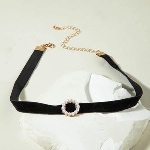 Close-up van zwarte fluwelen choker met parelcirkel hanger en verstelbare gouden sluiting