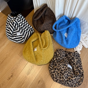 Flat lay of colorful plush tote bags in various patterns on a wooden floor