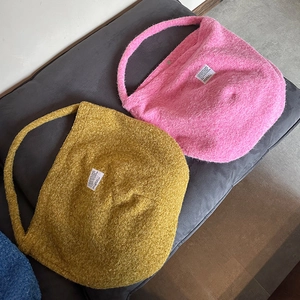 Detailed plush texture of pink and yellow faux lamb wool tote bags with woven label