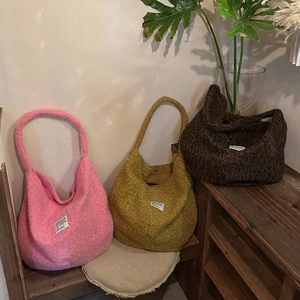 Macro detail of plush fleece tote bags in pink, yellow and brown with minimalist labels