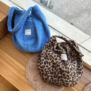 Detail of plush fleece oversized crossbody bags in cobalt blue and leopard print patterns