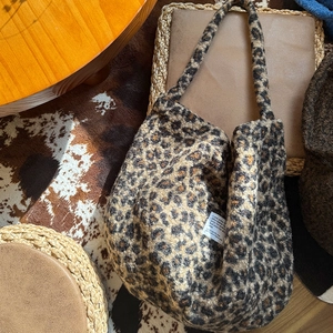 Top view of leopard print plush tote bag on a cozy wooden desk with woven mats