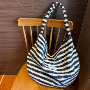 Detailed texture of black and white striped knit tote bag on a wooden chair