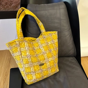 Dettaglio borsa tote in tweed a quadri gialli con etichetta in metallo fatta a mano