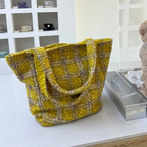 Dettaglio della borsa tote in peluche a quadri gialli con trama soffice e logo