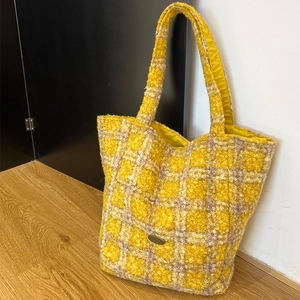 Dettaglio della borsa tote in peluche a quadri gialli con emblema in metallo