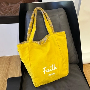 Dettaglio della borsa tote gialla con stampa Faith mole su tessuto strutturato e manici tessuti