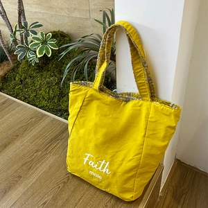 Dettaglio della borsa tote in nylon giallo con stampa Faith e fodera in peluche