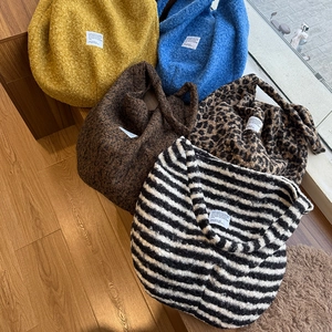 Large plush crossbody tote bags in five colors on wooden stairs under natural light