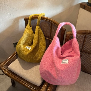 Large plush hobo bags in ginger and bright pink on a vintage rattan chair