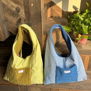 Detail of plaid tote bag featuring a large faux fur pocket and soft warm texture