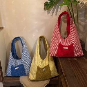 Close-up of winter tote bags in blue, yellow, and red with gingham and teddy fleece texture