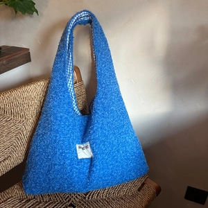 Detail of blue teddy plush tote bag featuring a checkered lining on a wicker chair