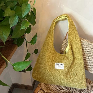 Detail of plush mustard yellow tote bag with SEE YOU patch on vintage chair
