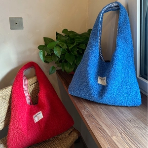 Detailed view of plush tote bags with plaid lining and See You stitched label