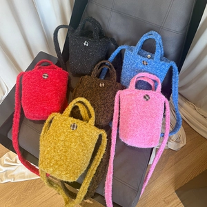 Détail des mini sacs en peluche en six couleurs disposés sur une chaise noire