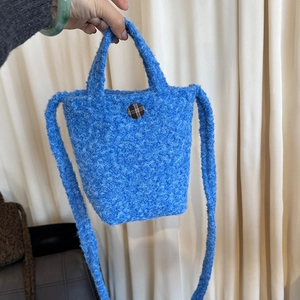 Détail du sac bandoulière en peluche bleue avec texture sherpa et bouton à carreaux