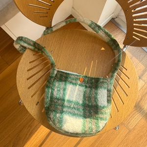 Green and white plaid lamb wool crossbody bag with a distinctive orange button accent