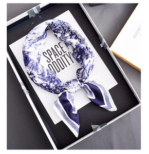 Detail view of blue and white silk scarf with toile de jouy pattern in gift box
