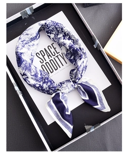 Detail of blue and white Toile de Jouy printed silk scarf tied in a bow in a gift box