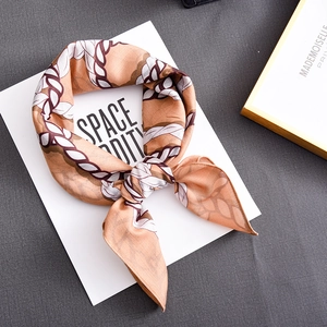Caramel silk scarf with woven chain pattern folded in an elegant bow tie style