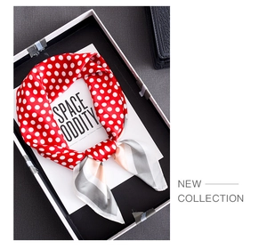 Detail of red and white polka dot silk scarf with striped borders on a tray