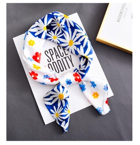 Detailed macro view of floral silk scarf featuring blue daisy and white wildflower print