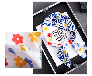 Close-up of silk-textured square scarf featuring vibrant floral daisy prints and split design
